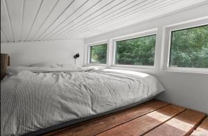 Un dormitorio blanco con una cama y dos ventanas. en Sjöutsikt Sövde, en Sövde