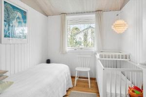 a small white bedroom with a bed and a window at 3004-Stege-Paelen-21 in Stege