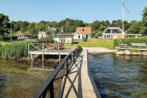 Un puente de madera sobre un río con casas al fondo. en 8254-Vordingborg-Masnedovej-34, en Ore