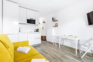 a living room with a yellow couch and a kitchen at Hostdomus - Yellow Suite in Sestriere +24 photos