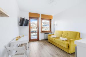 a living room with a yellow couch and a table at Hostdomus - Yellow Suite in Sestriere