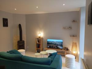 a living room with a blue couch and a tv at Gite La maison du gardien in Marcillac-Vallon