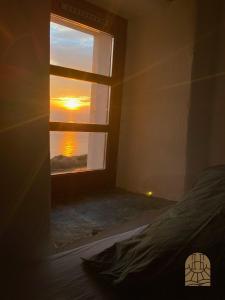 Una habitación con una ventana con una puesta de sol en el horizonte. en Cap Hélios, Centuri, en Morsiglia