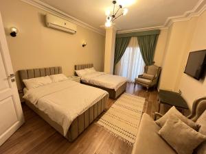 a bedroom with two beds and a couch and a tv at Sela 1 in Cairo