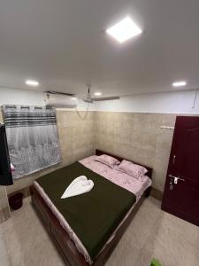 AR lodge في تيروفانمالي: غرفة نوم مع سرير مع قبعة عليه +صورتان