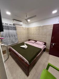 AR lodge في تيروفانمالي: غرفة نوم بسرير كبير مع بطانية خضراء