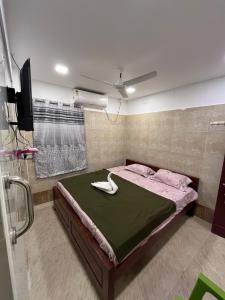 AR lodge في تيروفانمالي: غرفة نوم بسرير مع مروحة وتلفزيون