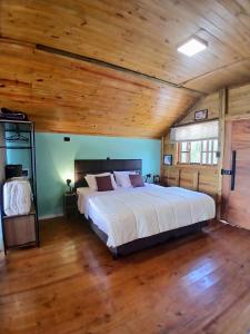 a bedroom with a large bed in a room with wooden ceilings at Scandinavian Lodge - Jacuzzi Privativa in Campos do Jordão