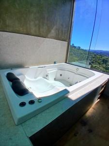 a bath tub in front of a large window at Scandinavian Lodge - Jacuzzi Privativa in Campos do Jordão +26 photos