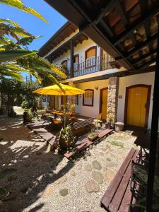 a patio with a table and a yellow umbrella at Pousada Solar do Algarve in Paraty