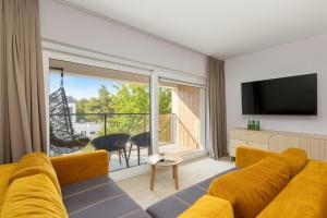 a living room with a yellow couch and a large window at Apartamenty Joy Me Łukęcin in Łukęcin