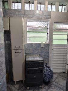 eine Küche mit einem Herd, einem Kühlschrank und einem Fenster in der Unterkunft loft anagro 103 in Ubatuba + 27 Fotos