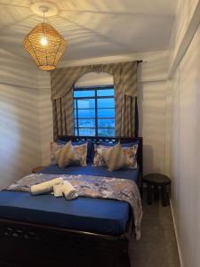 Nzuri Apartment في كيزيمو: غرفة نوم بسرير ازرق مع نافذة