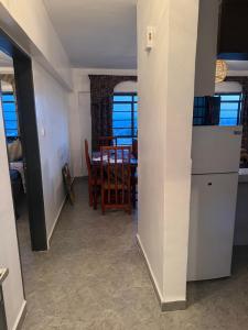 Nzuri Apartment في كيزيمو: مطبخ وغرفة طعام مع طاولة وكراسي