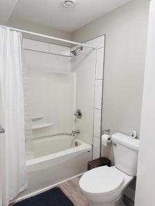 a white bathroom with a toilet and a bath tub at Moon's Suite near the New Hospital in Corner Brook +13 photos