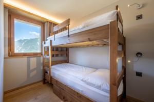 a bunk bed room with two bunk beds and a window at SWISSPEAK Resorts Vercorin in Vercorin