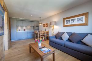 a living room with a blue couch and a table at SWISSPEAK Resorts by Pierre & Vacances Premium Vercorin in Vercorin