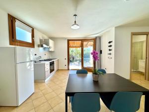 cocina con mesa negra y sillas azules en Cronta Apartments, en Bari Sardo