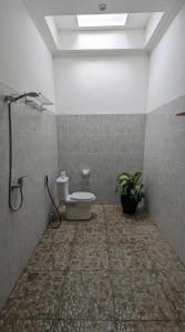 a bathroom with a toilet and a plant in it at Room #1 Mari Posa Cottage in Badung
