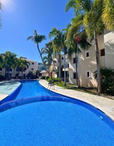 a large swimming pool with palm trees in front of a building at Apartamento con Piscina 2 Habitaciones Cerca de la Playa Bavaro in Punta Cana