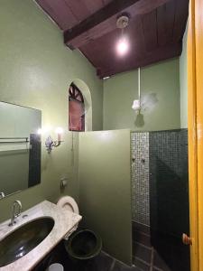a green bathroom with a sink and a shower at Pousada Solar do Algarve in Paraty