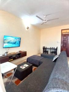 Una sala de estar con un sofá y un televisor de pantalla plana. en Escaped Diani, en Diani Beach