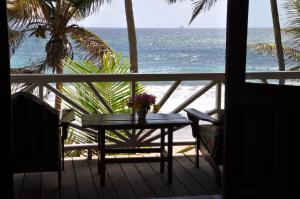 a table with a vase of flowers on a balcony overlooking the ocean at Petite Anse Hotel in Mount Alexander