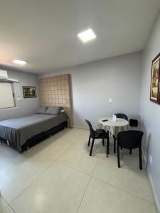 a bedroom with a bed and a table and chairs at Loft funcional no centro! in Foz do Iguaçu
