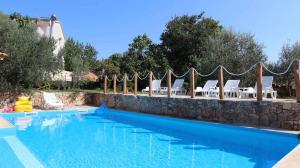 a large swimming pool with chairs and a stone wall at Apartment Malinska, Primorje-Gorski Kotar 20 in Sveti Vid-Miholjice