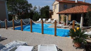 a swimming pool with chairs next to a house at Apartment Malinska, Primorje-Gorski Kotar 20 in Sveti Vid-Miholjice +7 photos