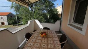 a table on a balcony with a bowl of fruit on it at Apartment Malinska, Primorje-Gorski Kotar 20 in Sveti Vid-Miholjice