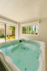eine große Badewanne in einem Raum mit Fenstern in der Unterkunft La Coccinelle- Gîte familial, Spa & Sauna in Lafrançaise