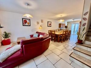 ein Wohnzimmer mit einem roten Sofa und einem Esszimmer in der Unterkunft La Coccinelle- Gîte familial, Spa & Sauna in Lafrançaise