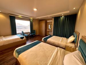 a hotel room with three beds and a window at Gabry Pyramids And Grand Egyptian Museum View Hotel in Cairo