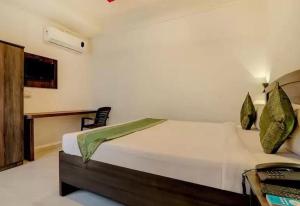 コールハープルにあるSuman Lodging near Mahalaxmi Temple, Kolhapurのベッドと机が置かれた寝室