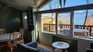 ein Wohnzimmer mit großem Fenster und Tisch in der Unterkunft La perle du lac - Némausa location in Chorges