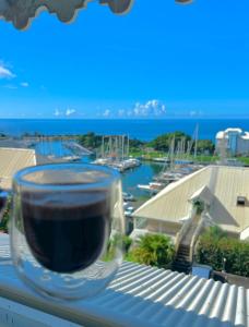 een kopje koffie zittend op een vensterbank bij Logement vue mer à 400 m de la plage in Gourbeyre
