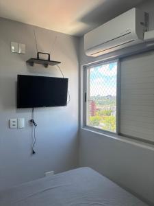 a bedroom with a flat screen tv and a window at Loft funcional no centro! in Foz do Iguaçu