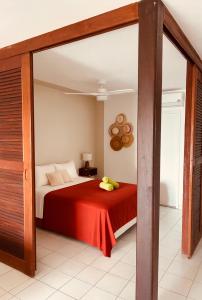 een slaapkamer met een bed met een rode deken bij Logement vue mer à 400 m de la plage in Gourbeyre