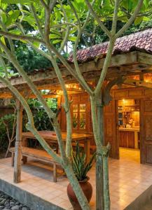 a wooden building with a bench and a tree at Room #3 Mari Posa Cottage in Badung