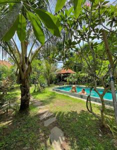 a pool in a garden with two people swimming at Room #3 Mari Posa Cottage in Badung