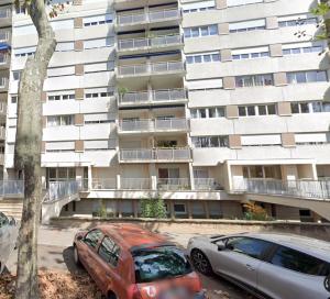 two cars parked in front of a large building at Le Bleu des Remparts in Chalon-sur-Saône