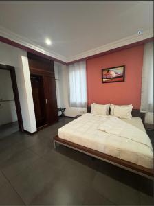 a bedroom with a large bed with an orange wall at Maxlot Hotel in Accra