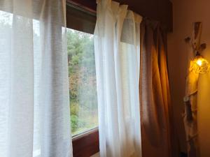 a window with white curtains in a room at Apartamento Cumbre Loba in La Pinilla +2 photos