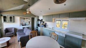 eine Küche und ein Wohnzimmer mit Sofa und Tisch in der Unterkunft La perle du lac - Némausa location in Chorges