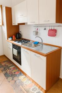 a kitchen with white cabinets and a sink and a stove at Salina Castel Vinci in Rinella +21 photos