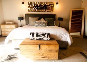 a bedroom with a large bed with a wooden trunk at Nzenga Lodge in Hoedspruit