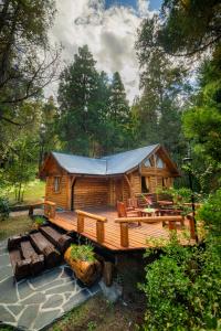 a cabin in the woods with a large deck at Complejo Palo Quemado in El Hoyo