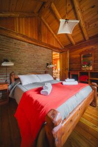 a bedroom with a large bed with a red blanket at Complejo Palo Quemado in El Hoyo