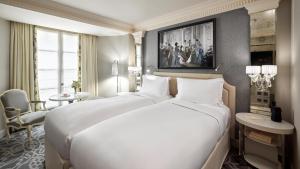 a bedroom with a large white bed and a desk at Sofitel Paris Le Faubourg in Paris